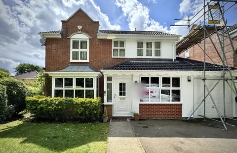 After: front of a detached brick and render house in sunshine, with white render, fascias and soffits