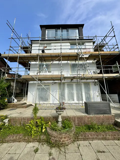 Rear of a three-storey house under full scaffold with every window and door sheeted in polythene