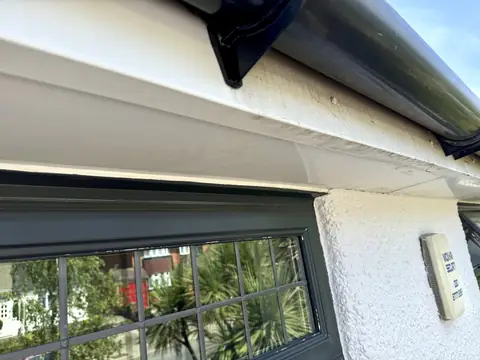 UPVC fascia half cleaned, bright white on the left and grimy on the right, above a dark grey window