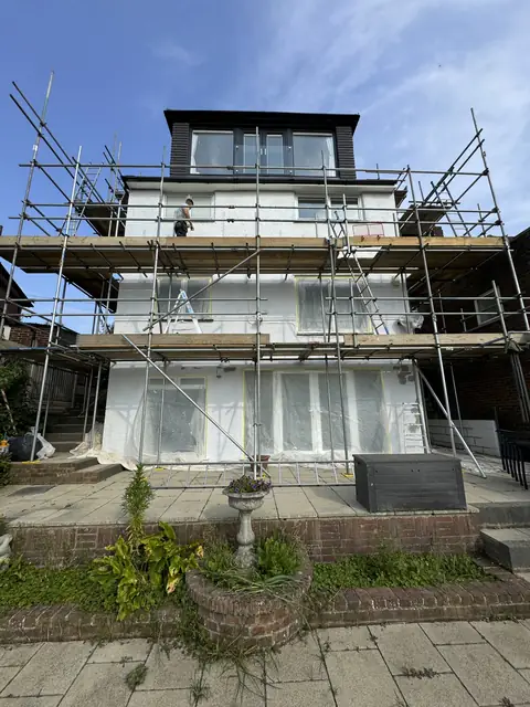 Tall rear elevation under three lifts of scaffold, upper walls painted white and ground floor windows sheeted