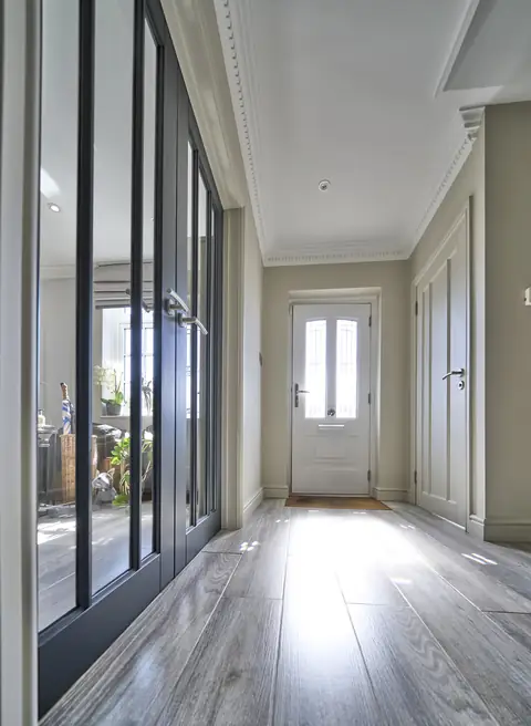Dark painted glazed double doors along a hallway leading to a white front door