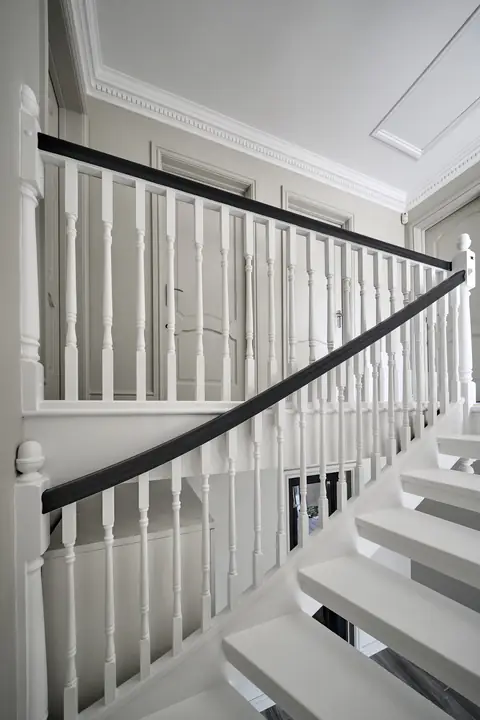White balustrade with a dark handrail running up an open-tread staircase to the landing