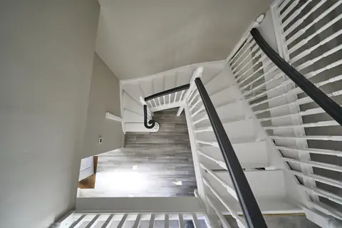Looking down the white painted staircase from the top landing, with dark handrails