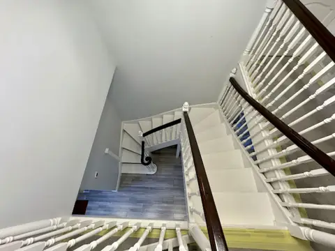 Looking down the stairwell during preparation, with dark wooden handrails and masking tape on the carpet