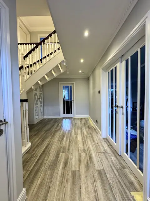 Hallway before decorating, with grey walls, white glazed double doors and a dark wooden handrail