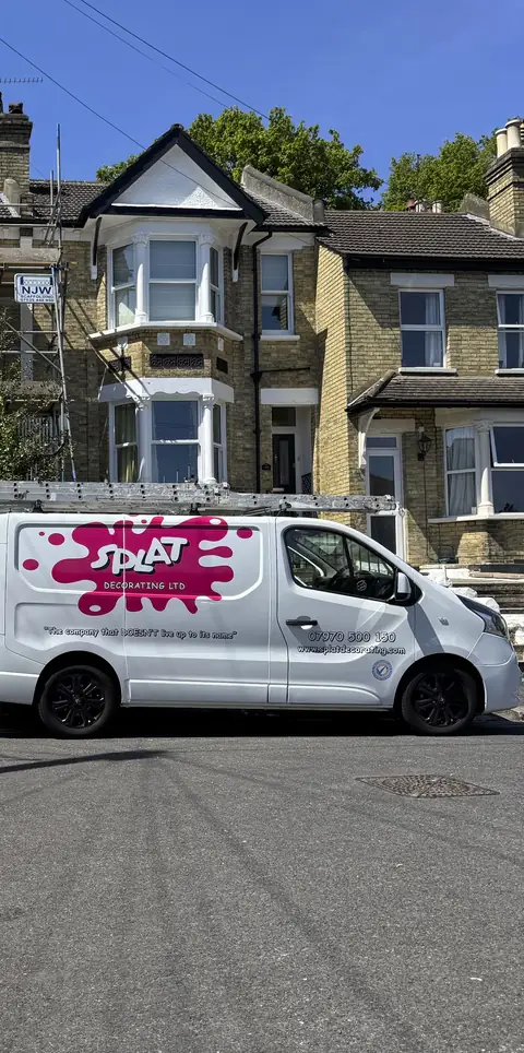 White Splat Decorating van with pink splat logo parked on the road outside a scaffolded Victorian house
