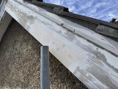 New timber patch in the barge board with screw holes filled and white spots of filler along the old timber