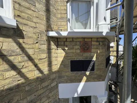 Bay window with a crisp white painted sill and white window head below, yellow brick with terracotta tile