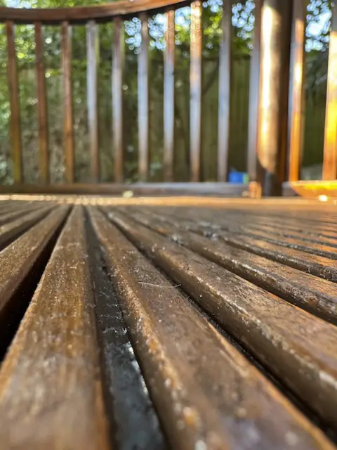 Low close-up of varnished grooved decking with sunlit spindles behind