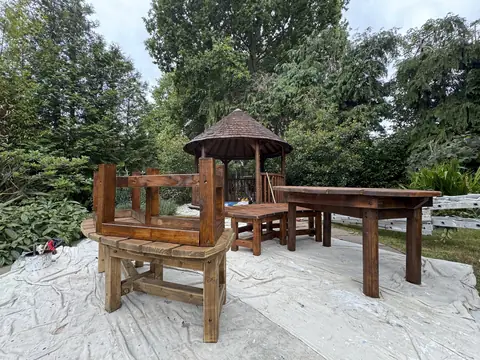 Garden bench turned upside down to coat its legs, with a varnished table and benches on dust sheets and the gazebo behind