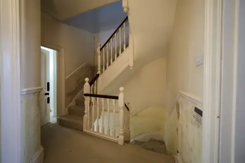 First floor landing and stairs up to the next floor, with the walls stripped below the dado rail