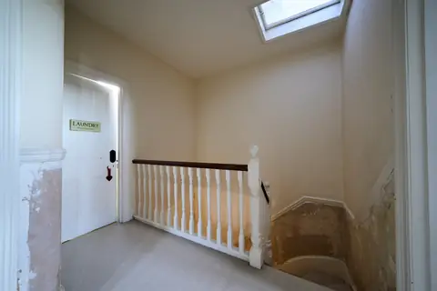 Top floor landing under a skylight with a white balustrade, cream walls and stripped walls down the stairs