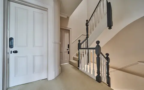 Landing with pink walls and doors, white spindles and dark painted newel posts and handrails