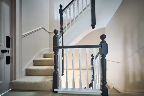 Dark painted newel posts and handrails with white spindles on a carpeted staircase