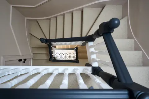 Overhead view of the winding carpeted staircase with dark handrails and white spindles