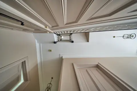 Looking straight up the three storey stairwell past pink panelling and doors to the top floor